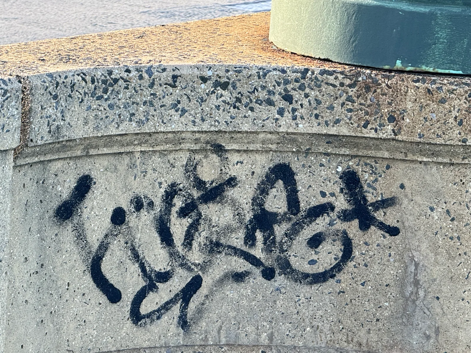 Blue spray-painted graffiti on a granite pier of the Francis Scott Key Bridge