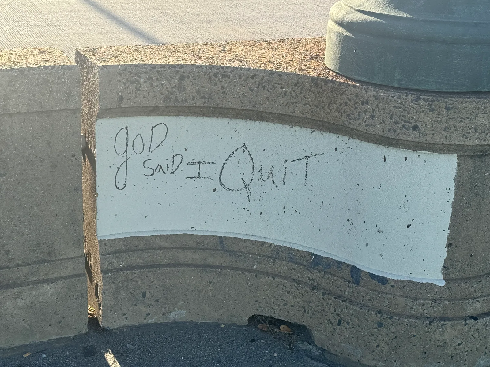 A patch of mismatched white paint covering graffiti on the bridge's barrier wall